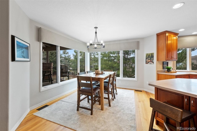 dining room with visible vents, a chandelier, light wood-style flooring, and baseboards