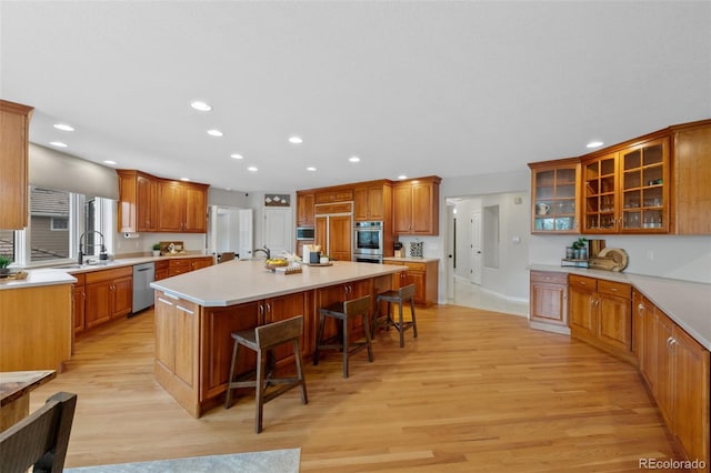 kitchen featuring a center island, a breakfast bar area, light countertops, light wood-style flooring, and appliances with stainless steel finishes