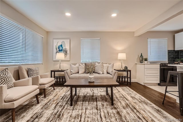 living room with beamed ceiling, a healthy amount of sunlight, and dark hardwood / wood-style floors