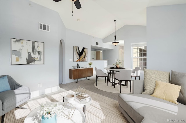 carpeted living room featuring ceiling fan and high vaulted ceiling