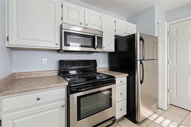 kitchen featuring appliances with stainless steel finishes, light tile patterned floors, and white cabinetry