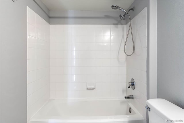 bathroom with tiled shower / bath combo and toilet