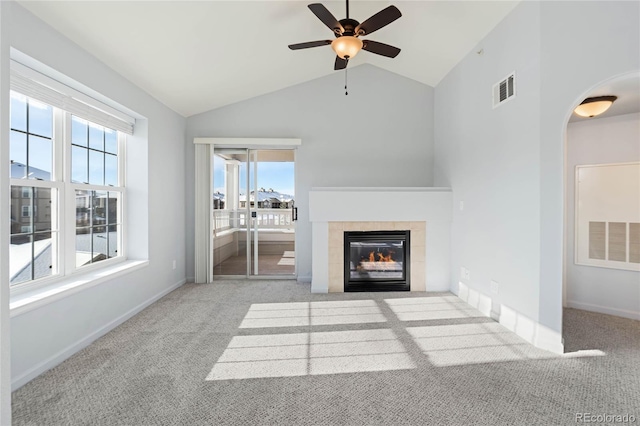 unfurnished living room featuring a tile fireplace, light carpet, plenty of natural light, and ceiling fan