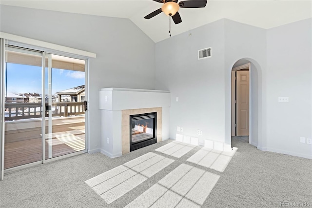 unfurnished living room featuring ceiling fan, light colored carpet, lofted ceiling, and a fireplace