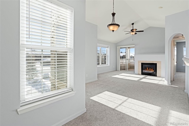 unfurnished living room featuring a tiled fireplace, light carpet, ceiling fan, and lofted ceiling