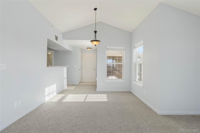 carpeted spare room with high vaulted ceiling