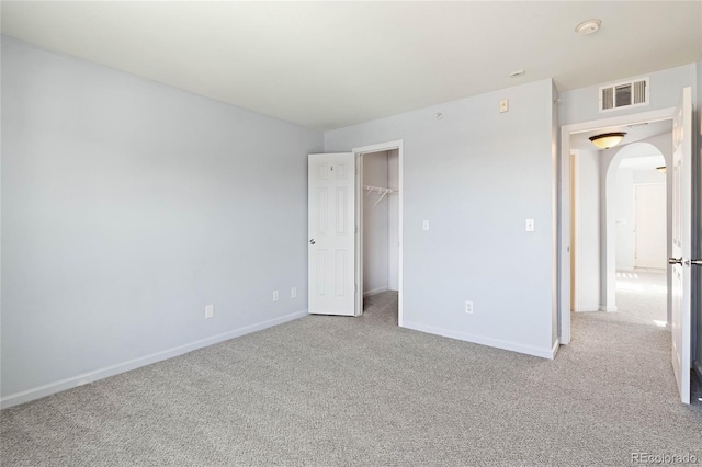 unfurnished bedroom with light colored carpet, a walk in closet, and a closet