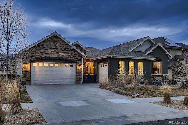 view of front of house featuring a garage, stone siding, driveway, and roof with shingles