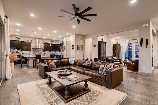 living area with light wood-type flooring, visible vents, and recessed lighting