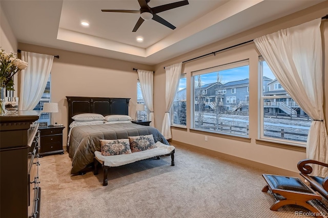 bedroom with ceiling fan, recessed lighting, light colored carpet, baseboards, and a tray ceiling