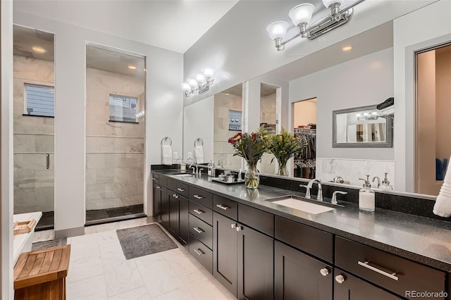 bathroom featuring double vanity, marble finish floor, a sink, and tiled shower