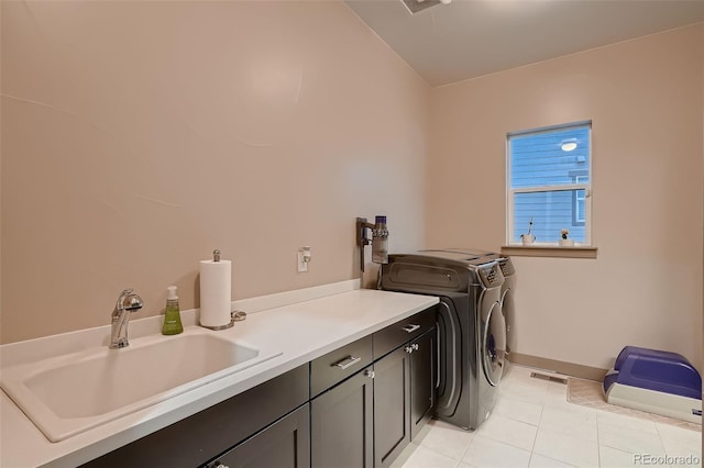 clothes washing area with light tile patterned floors, cabinet space, visible vents, a sink, and separate washer and dryer