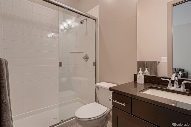 full bathroom featuring a shower stall, toilet, and vanity