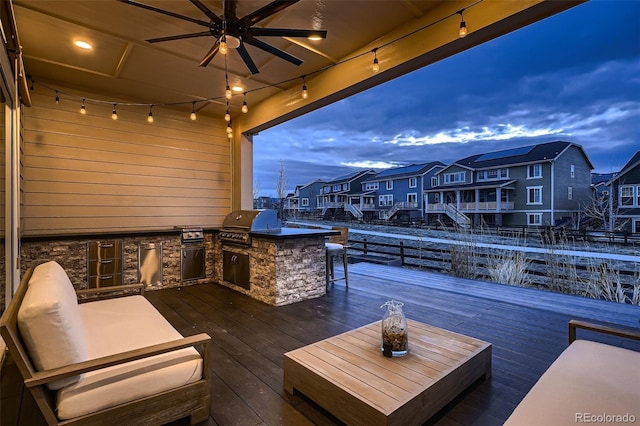 deck featuring ceiling fan, an outdoor kitchen, a grill, and a residential view