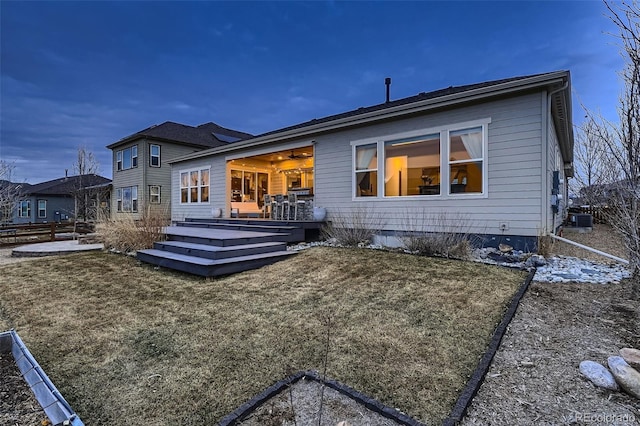 rear view of property featuring a lawn, central AC, and a wooden deck