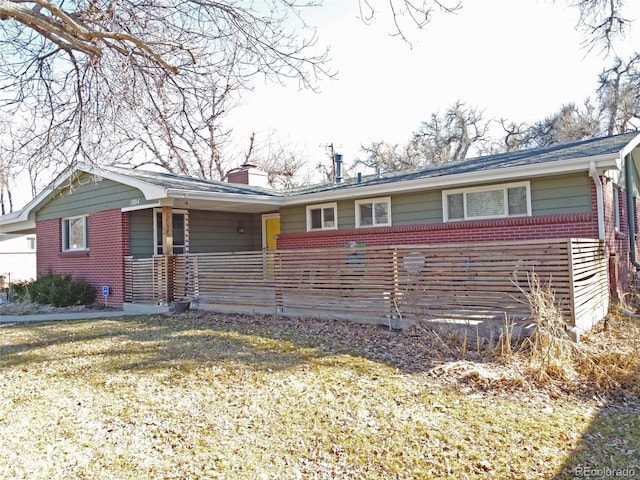 single story home featuring brick siding, covered porch, and a chimney