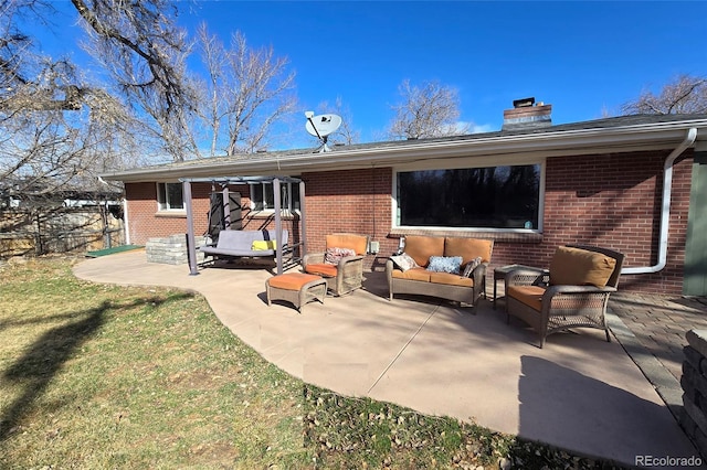 back of house with a patio, a yard, a chimney, brick siding, and an outdoor hangout area