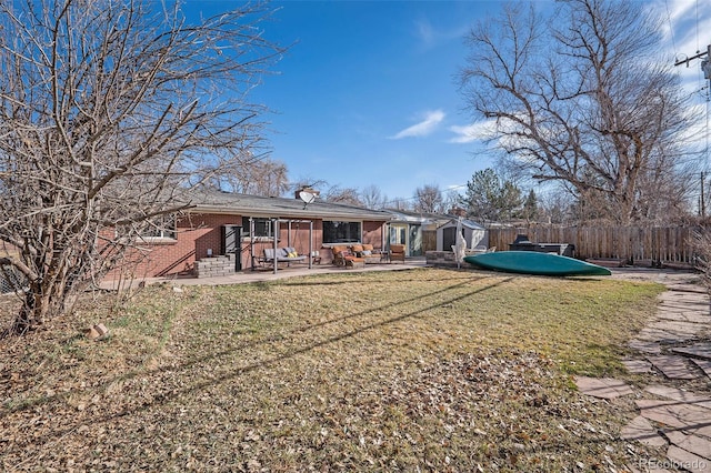 rear view of property featuring fence, a yard, entry steps, a patio area, and brick siding