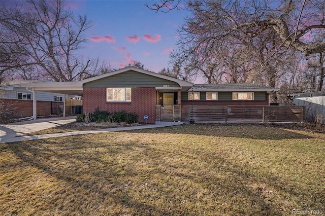 ranch-style home with driveway, fence, a yard, a carport, and brick siding