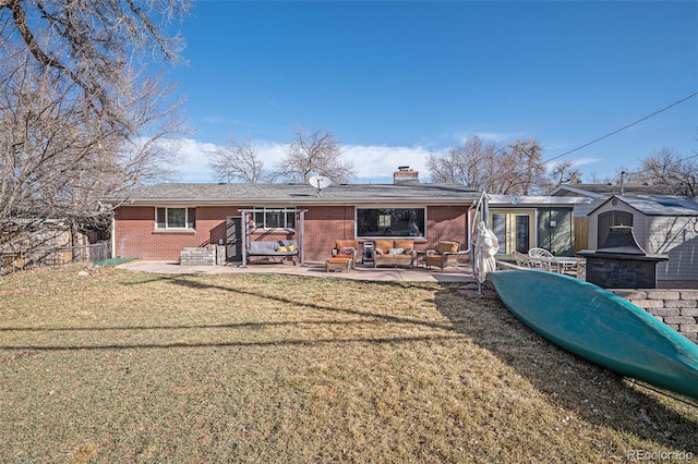 back of property with brick siding, a chimney, a lawn, and a patio area