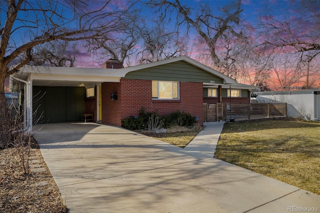 view of front of home featuring a front yard, concrete driveway, brick siding, and a chimney