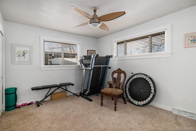 exercise room with baseboards, visible vents, carpet floors, and ceiling fan