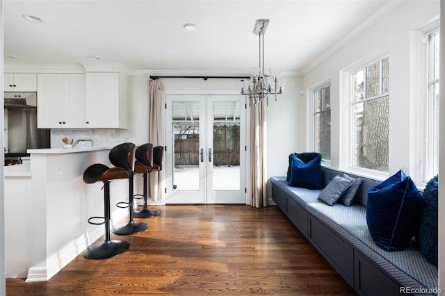 interior space with dark wood-type flooring, a notable chandelier, ornamental molding, and french doors