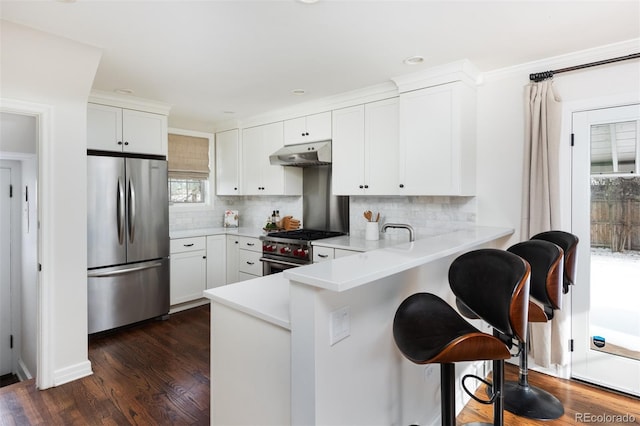 kitchen with white cabinetry, kitchen peninsula, backsplash, stainless steel appliances, and a breakfast bar area