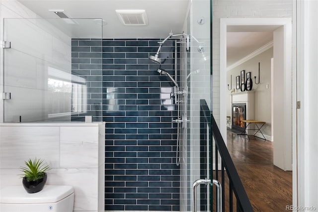 bathroom with wood-type flooring, toilet, ornamental molding, and an enclosed shower