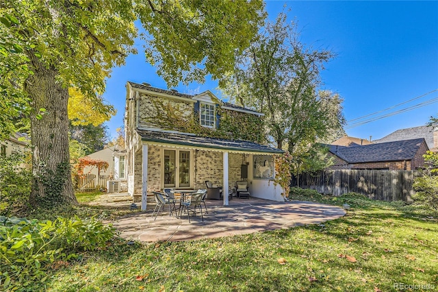 rear view of property with a patio area, a lawn, and french doors