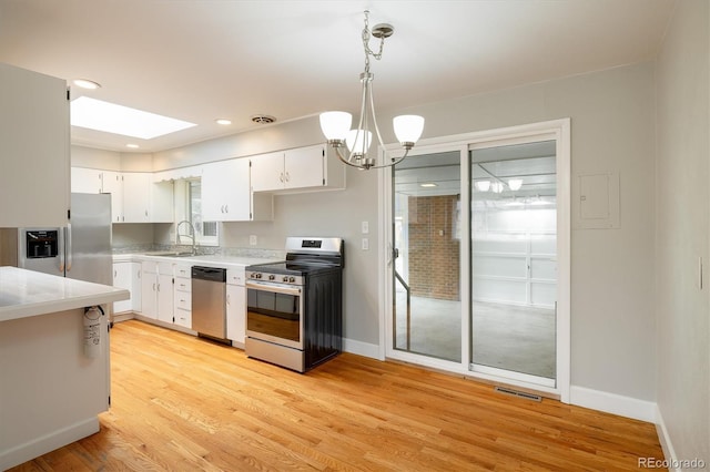 kitchen featuring stainless steel appliances, sink, decorative light fixtures, an inviting chandelier, and white cabinets