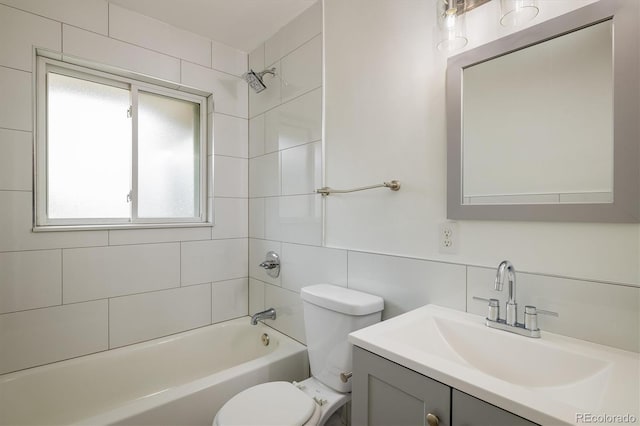 full bathroom with vanity, tiled shower / bath combo, toilet, and tile walls