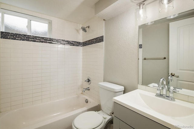 full bathroom featuring tiled shower / bath, vanity, and toilet