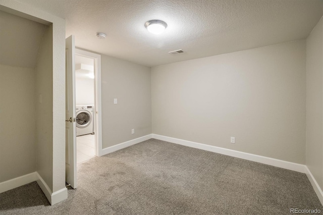 unfurnished room featuring light carpet, washer / dryer, and a textured ceiling