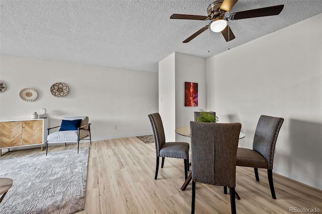 dining area featuring ceiling fan, light hardwood / wood-style floors, and a textured ceiling