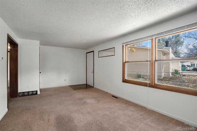 spare room with light carpet and a textured ceiling