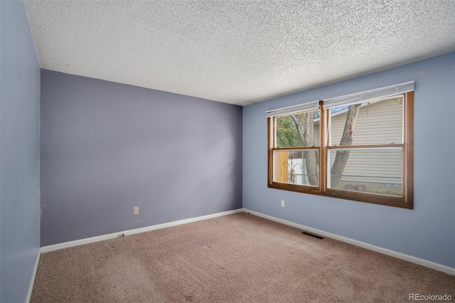 carpeted empty room featuring a textured ceiling