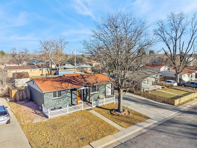 view of front of home with concrete driveway, brick siding, a residential view, and a fenced front yard