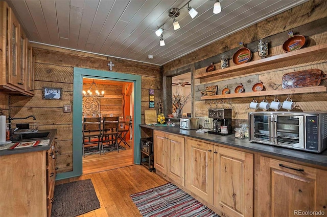 kitchen featuring wood walls, sink, light hardwood / wood-style flooring, a notable chandelier, and a fireplace