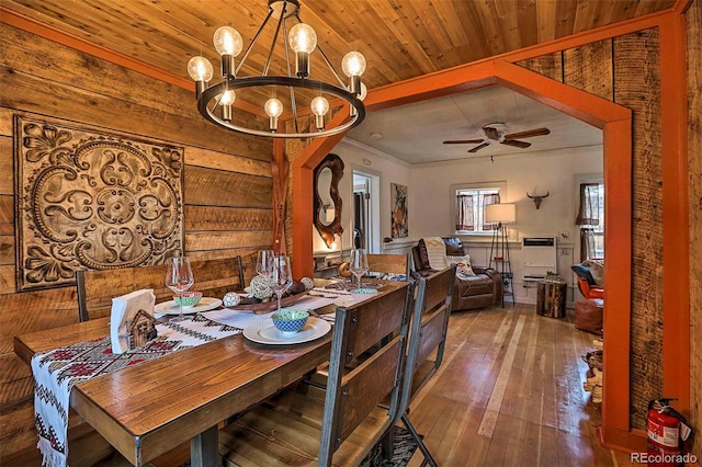 dining room featuring ceiling fan with notable chandelier, wood ceiling, wood walls, and hardwood / wood-style flooring