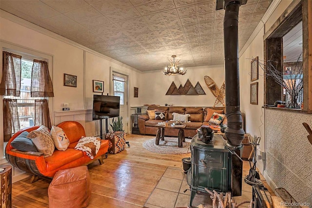 living room featuring a wood stove, a chandelier, hardwood / wood-style flooring, and crown molding