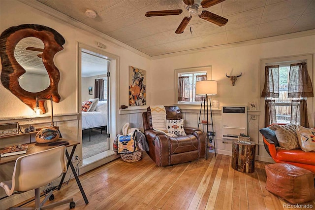 living room with heating unit, light hardwood / wood-style floors, ceiling fan, and crown molding