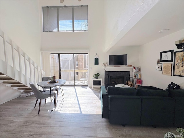 living room featuring stairs, a high ceiling, a fireplace, and wood finished floors