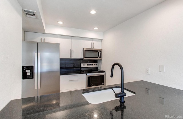 kitchen featuring a sink, visible vents, white cabinets, appliances with stainless steel finishes, and backsplash