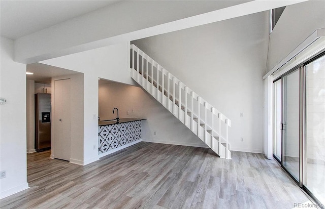 interior space with a sink, stairway, baseboards, and wood finished floors