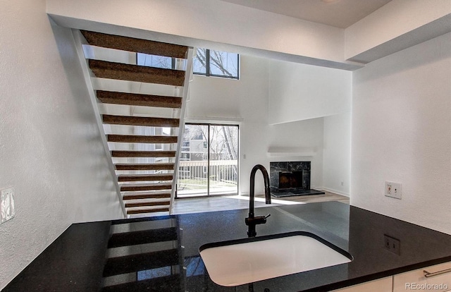 kitchen featuring a textured wall, a premium fireplace, a sink, open floor plan, and dark countertops