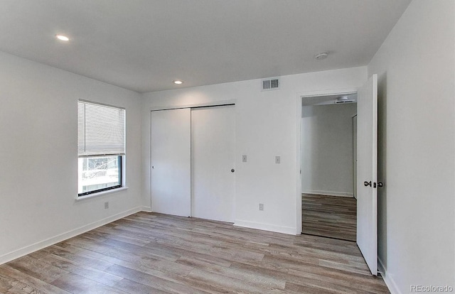 unfurnished bedroom featuring a closet, wood finished floors, visible vents, and recessed lighting