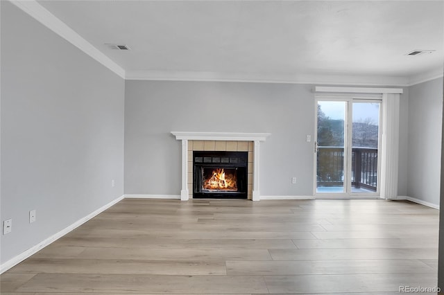 unfurnished living room with a tile fireplace, crown molding, and light hardwood / wood-style flooring