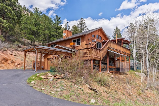29 Cedar Ln, Bailey, CO 80421 - view of front facade with a wooden deck, a chimney, a garage, driveway, and a carport
