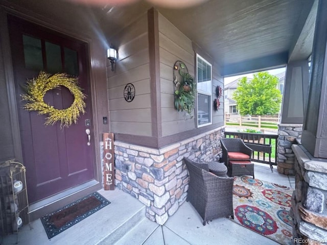 entrance to property featuring stone siding and a porch